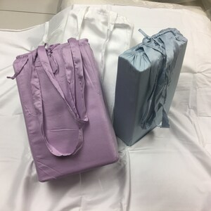 Könnte beinhalten: Zwei Bettwäsche-Sets in hellblau und Lavendel. Die Bettwäsche ist gefaltet und auf einer weißen Oberfläche gestapelt. Die Bettwäsche hat ein schlichtes Design und ist aus einem weichen, komfortablen Stoff gefertigt.