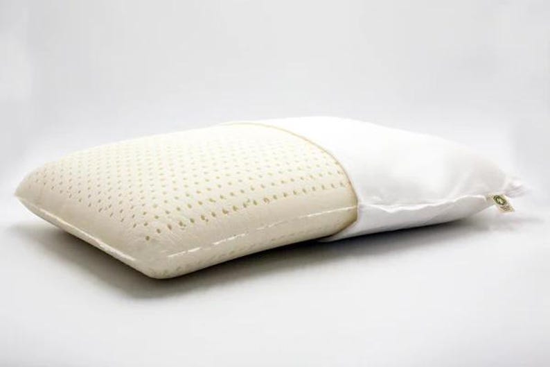 May include: A white latex pillow with a breathable, perforated surface and a removable white cotton cover. The pillow is designed for comfortable sleep and support.