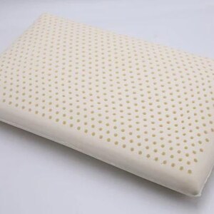 May include: A white latex pillow with a pattern of small holes. The pillow is designed for sleeping and is made of a breathable material.