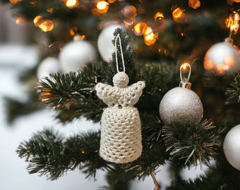 Könnte beinhalten: Ein weißer Häkelengel-Anhänger, der an einem Weihnachtsbaum mit silbernen Kugeln und Lichterketten hängt.
