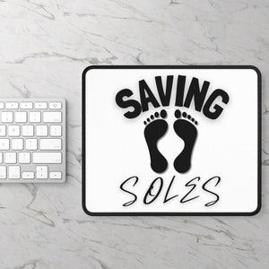 May include: A white mousepad with black text that reads "SAVING SOLES" and two black footprints.
