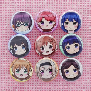 May include: Nine round anime-style character buttons with different hair colors and facial expressions. Each button features a smiling face with large eyes and a unique background color, including purple, pink, blue, and green.