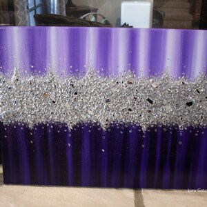 May include: Purple and silver abstract painting with a textured silver glitter layer. The painting is on a canvas and has a white border.