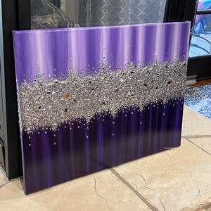 May include: Purple and silver abstract painting with a textured silver glitter layer. The painting is on a canvas and has a white border.