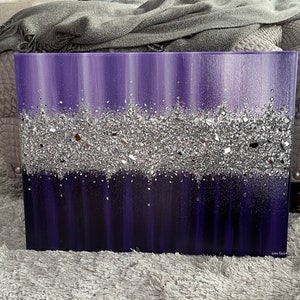 May include: Purple and silver abstract painting with a textured silver glitter layer. The painting is on a canvas and has a white border.