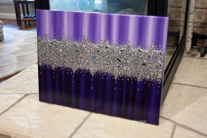 May include: Purple and silver abstract painting with a textured glitter finish. The painting has a vertical stripe pattern and the glitter is concentrated in a horizontal band across the middle of the painting.