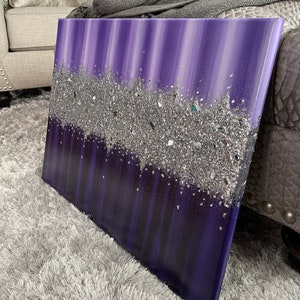 May include: Purple and silver abstract painting with a textured glitter finish. The painting has a vertical striped pattern and a layer of silver glitter that creates a sparkling effect.