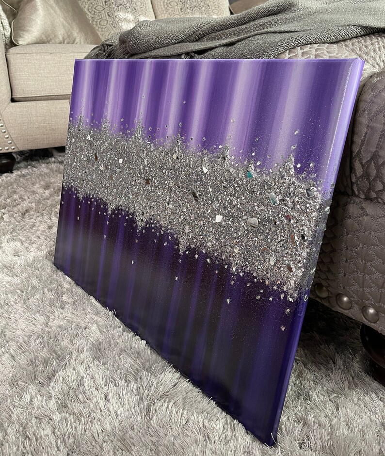 May include: Purple and silver abstract painting with a textured glitter finish. The painting has a vertical striped pattern and a layer of silver glitter that creates a sparkling effect.