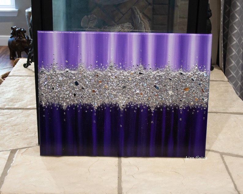 May include: Purple and silver abstract painting with a band of silver glitter across the middle. The painting is on a canvas and has a white background.