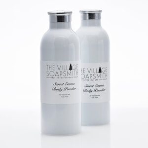 May include: Two white bottles of Sweet Emma Body Powder by The Village Soapsmith. The bottles have silver lids and are labeled with the company name and product name.