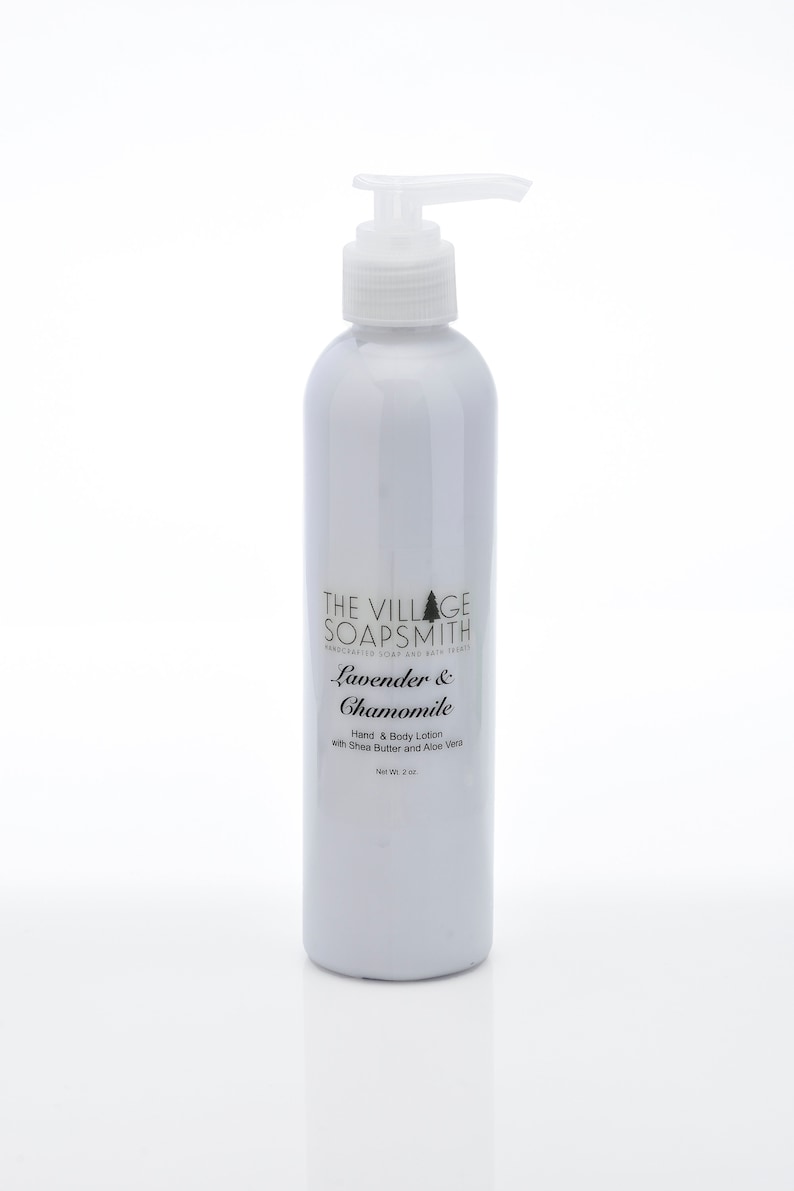 K&ouml;nnte beinhalten: Eine wei&szlig;e Flasche mit Lavendel- & Kamillen-Hand- und K&ouml;rperlotion mit einem Pumpspender. Die Flasche ist mit "The Village Soapsmith" beschriftet und hat ein Nettogewicht von 2 oz.
