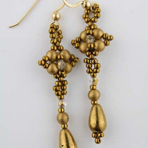 May include: Gold beaded earrings with a teardrop design and a crystal accent. The earrings are made with small gold beads and have a delicate, feminine look.
