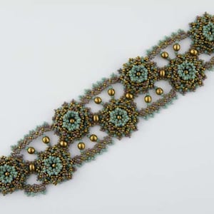 Könnte beinhalten: Ein Armband aus Perlen mit einem sich wiederholenden Muster aus grünen und goldenen sternförmigen Motiven. Das Armband ist aus kleinen Perlen gefertigt und hat ein zartes, filigranes Design.