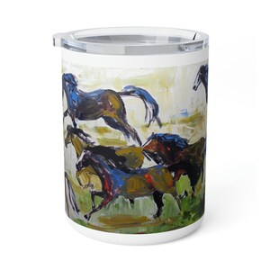 May include: A white ceramic travel mug with a colorful abstract painting of a herd of horses running. The horses are painted in shades of brown, blue, and green.