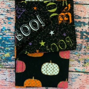 Könnte beinhalten: Schwarze Leggings mit einem glitzernden schwarzen Stoff mit dem Wort "BOO!" und Sternen. Die Leggings haben eine zweite Schicht aus schwarzem Stoff mit einem Kürbis-Muster in Orange, Weiß und Rosa.