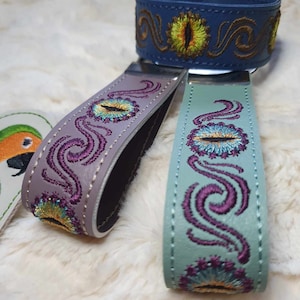 May include: Three leather keychains with embroidered eye designs. The keychains are in shades of blue, purple, and green.