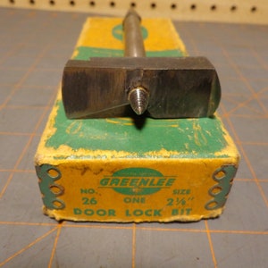 May include: A Greenlee door lock bit in a yellow and green box. The bit is 2 1/4 inches in size and is labeled "No. 26 One Door Lock Bit".