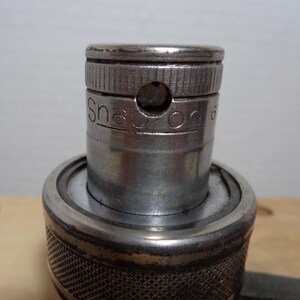 May include: Close-up of a silver Snap-on socket wrench. The wrench has a textured handle and the brand name is visible on the side. The top of the wrench has a small hole.