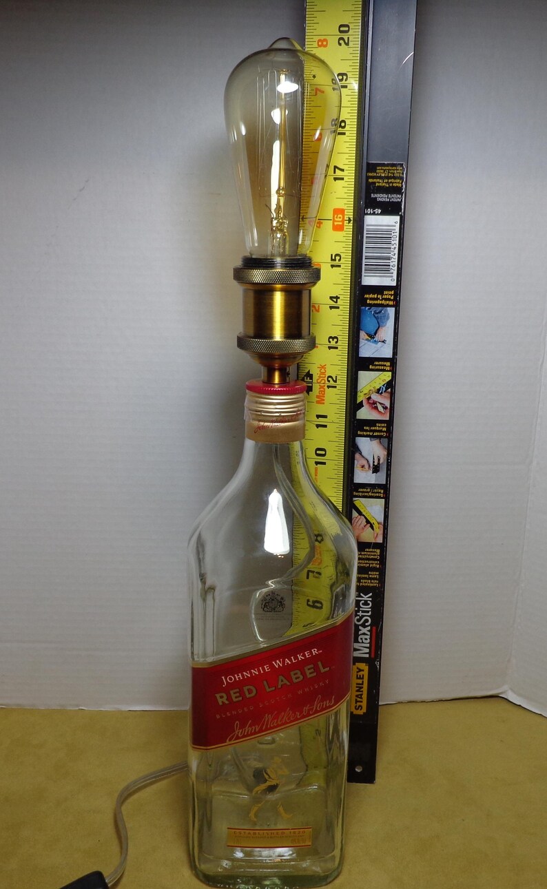 K&ouml;nnte beinhalten: Eine umfunktionierte Lampe aus einer Johnnie Walker Red Label Whiskyflasche. Die Lampe hat eine gro&szlig;e Edison-Gl&uuml;hbirne, messingfarbene Hardware und ein rotes Etikett. Die Lampe ist etwa 51 cm hoch.