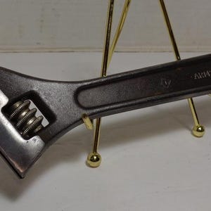 May include: A black adjustable wrench with a silver spring mechanism and the text "A.W.C. 1000" on the handle.