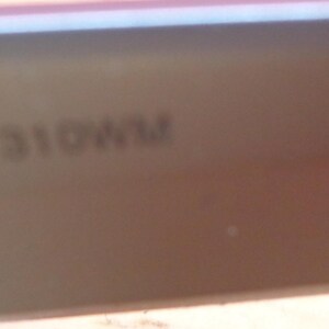 May include: A close-up of a section of a light brown object with the text "CAB1310WM" printed on it. The object appears to be a part of a larger item, possibly a piece of furniture or a vehicle component.