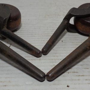 May include: Four antique wooden caster wheels with metal swivel brackets and metal stems. The wheels are brown and the metal is a dark gray.