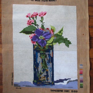 Puede incluir: Un lienzo de punto de aguja con un bodegón de flores rosas y moradas en un jarrón azul. El lienzo está etiquetado con "COLLECTION 'GRANDS MAÎTRES' LE VASE d'après MANET TAPISSERIE DMC B 619".