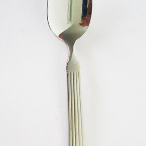 May include: A silver spoon with a rounded bowl and a fluted handle.