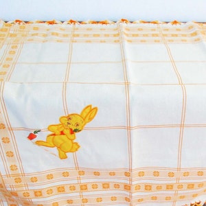 May include: White tablecloth with orange and yellow embroidered details. The tablecloth has a checkered pattern and a small embroidered bunny holding a carrot.