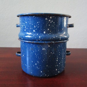 Peut inclure: Une marmite en émail bleu en deux parties avec des mouchetures blanches. La marmite a deux poignées sur chaque partie et un bord roulé. L'émail a un aspect vintage, avec quelques signes d'usure. La marmite est conçue pour la cuisine.