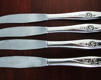 May include: Four silver dinner knives with rose designs on the handles.