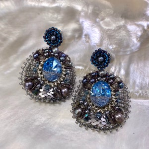 May include: A pair of silver and blue beaded earrings with a large blue crystal in the center of each earring.