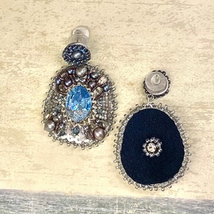 May include: A pair of dangle earrings with a blue gemstone and silver beads. One earring has a black fabric center and the other has a silver center.