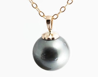 May include: A gold chain necklace with a large, dark gray pearl pendant.