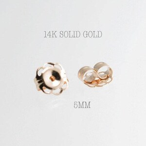 May include: Two 14K solid gold earring backs. One is a flower-shaped design, and the other is a butterfly-shaped design. The text in the image reads "14K SOLID GOLD" and "5MM".