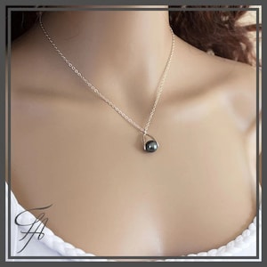 Pu&ograve; includere: Una collana a catena d'argento con un ciondolo di perla nera. La perla &egrave; incastonata in una cornice argentata che ricorda una lacrima.