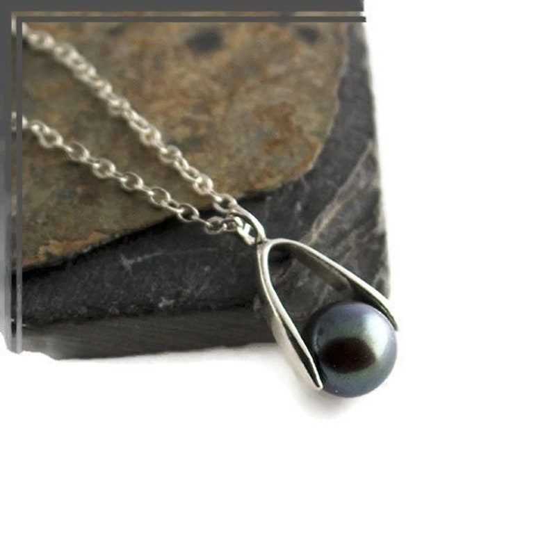 Pu&ograve; includere: Una collana d'argento con un ciondolo di perla nera. La perla &egrave; tenuta in una montatura d'argento che ricorda una lacrima.