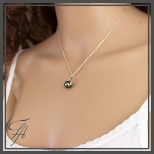 Pu&ograve; includere: Una collana a catena d'argento con un ciondolo a forma di perla verde scuro.