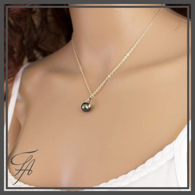 Pu&ograve; includere: Una collana a catena d'argento con un ciondolo a forma di perla verde scuro.