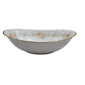 Może przedstawiać: Biała owalna miska do serwowania z kwiatowym wzorem w odcieniach pomarańczowego, zielonego i żółtego. Miska ma złotą obwódkę.