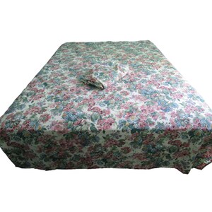 May include: A white bed sheet with a floral pattern in shades of pink, blue, and green. The sheet is folded and placed on top of a bed.