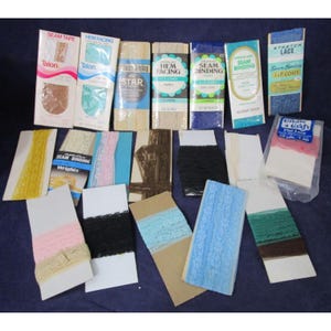 Könnte beinhalten: Eine Auswahl an Vintage-Nahtbändern und Spitzenborten in verschiedenen Farben und Mustern, darunter Weiß, Rosa, Blau, Braun und Schwarz. Die Borten sind in durchsichtigen Plastiktüten verpackt und mit Markennamen wie "Talon", "Wrights" und "Star" gekennzeichnet.
