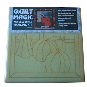 Puede incluir: Un kit cuadrado y beige de pared sin costura "Quilt Magic". El kit presenta un diseño de calabazas y una escena de ventana. El texto en el embalaje dice "Fácil y divertido de hacer" y "¡Resultados excelentes cada vez!"