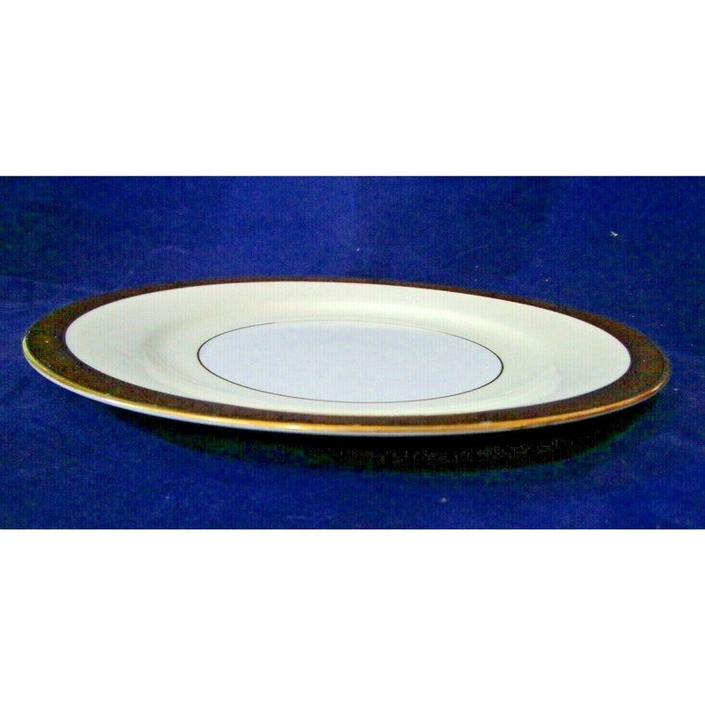 Op de afbeelding: Een wit keramiek dinerbord met een gouden rand. Het bord heeft een kleinere witte cirkel in het midden met een dunne gouden rand.