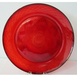 May include: A red glass dinner plate with a diamond pattern around the edge and a smaller diamond pattern in the center.