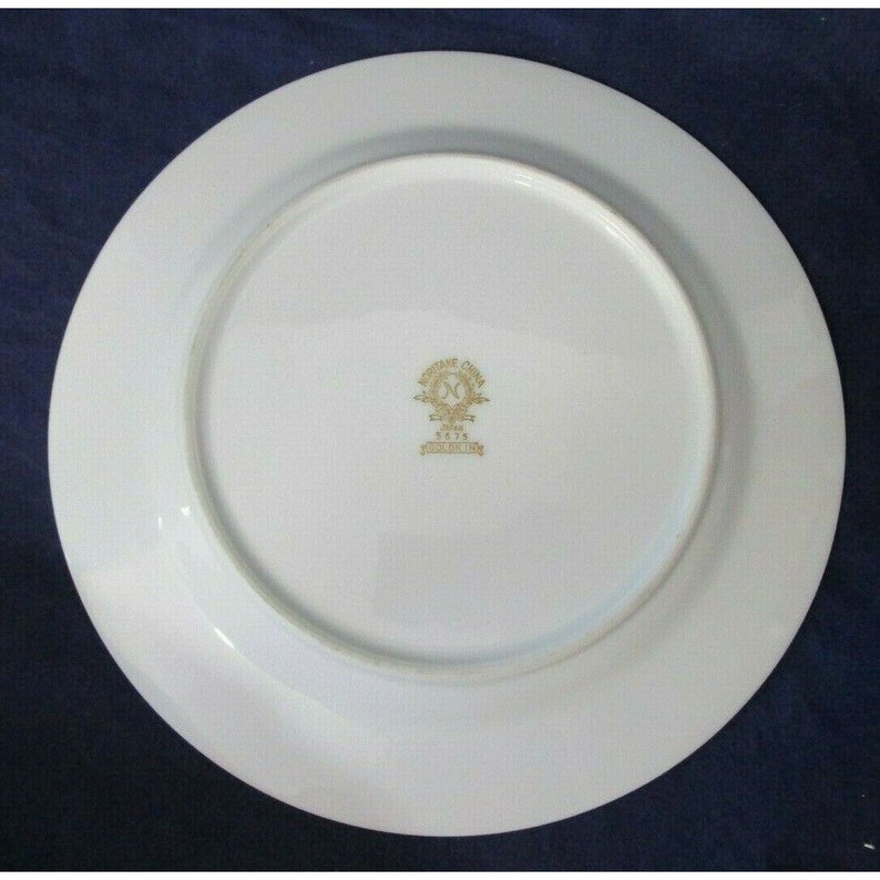 Op de afbeelding: Witte keramische plaat met een gouden rand en een gouden logo in het midden dat "Made in China" en "Royal Crown" met een kroon en het jaar "1974" in het midden van de kroon zegt.