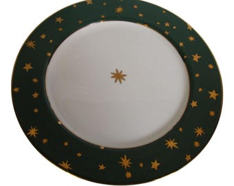 May include: A white plate with a dark green border adorned with gold stars. A single gold star is centered on the white interior. The plate has a gold trim. This decorative plate is suitable for serving food.