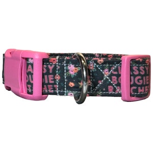 May include: A black and pink dog collar with a floral pattern and the text "Classy Bougie Ratchet" printed on it.
