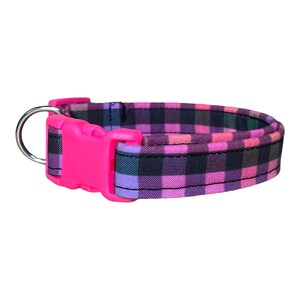 May include: A pink and black plaid dog collar with a pink plastic buckle and a silver D-ring.