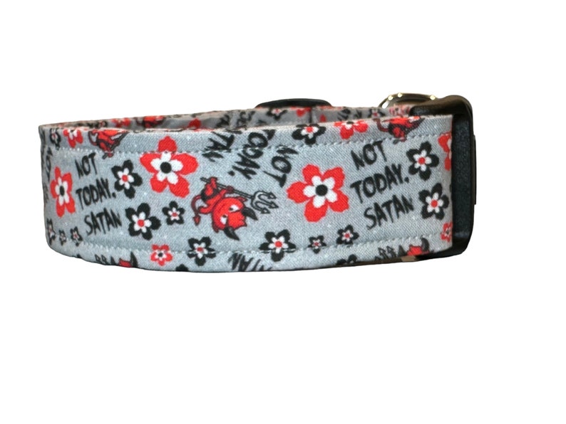 May include: A gray dog collar with a black buckle and a red and black floral pattern. The collar has the text "Not Today, Satan" printed on it.